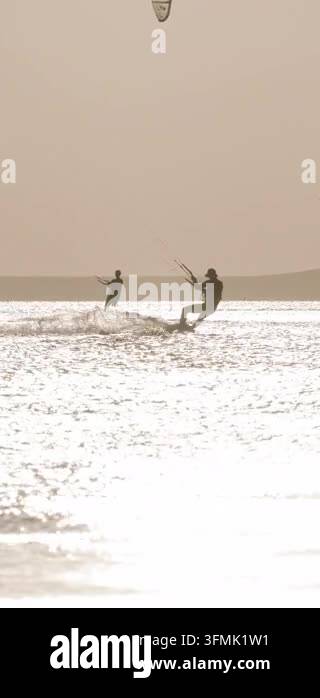 Kite surfer jumping high above the sea with kite against a golden sky ...