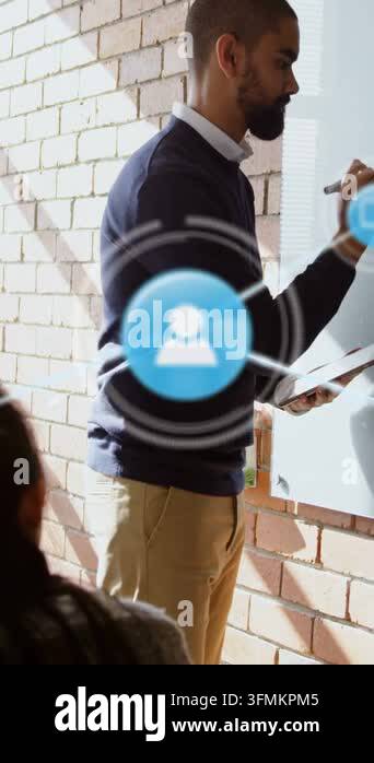 Male trainer writing with tablet causing blue icons linking notes while ...