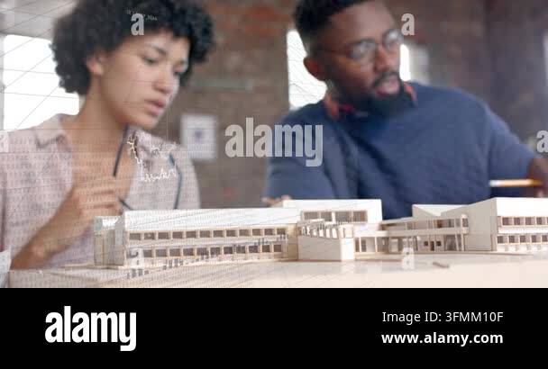 Two designers leaning over scale model, man pointing yellow pencil ...