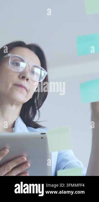 Businesswoman thinking, analyzing data on a digital tablet, standing ...