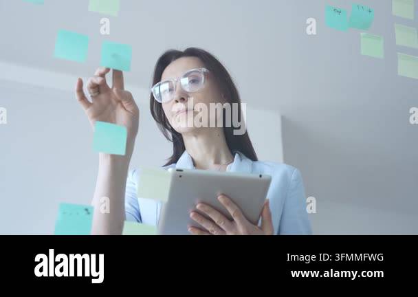 Businesswoman thinking, analyzing data on a digital tablet, standing ...