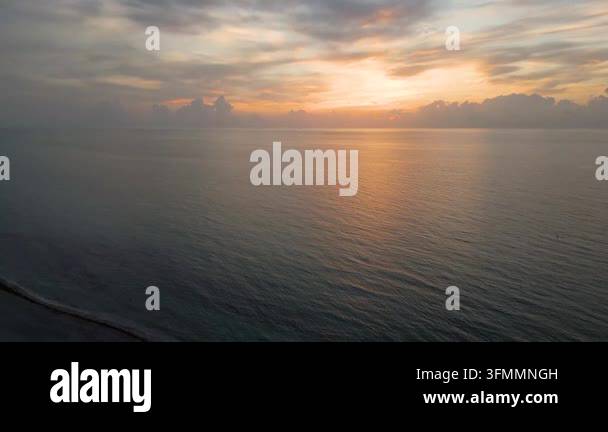 A drone glides low over an empty miami beach as the sky glows with soft ...