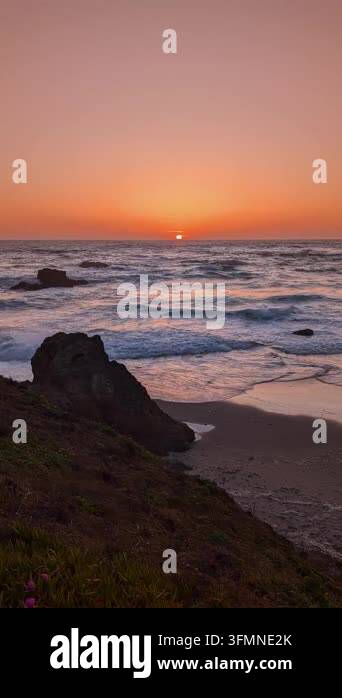 Sunset over ocean waves with rocks on sandy beach shoreline Stock Video ...