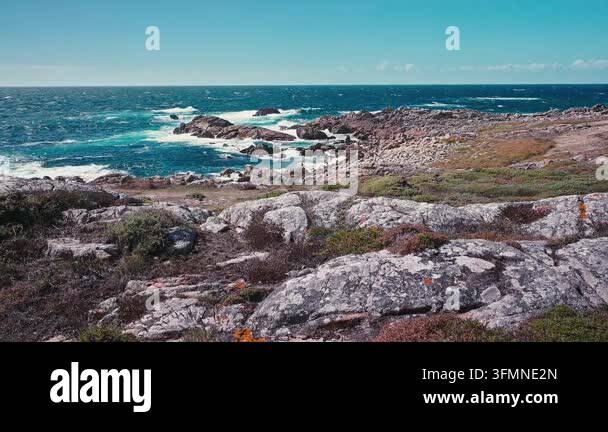 Rocky ocean coastline with blue waves crashing against the shore Stock ...