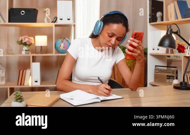 African American young woman on home table writes new foreign word in ...