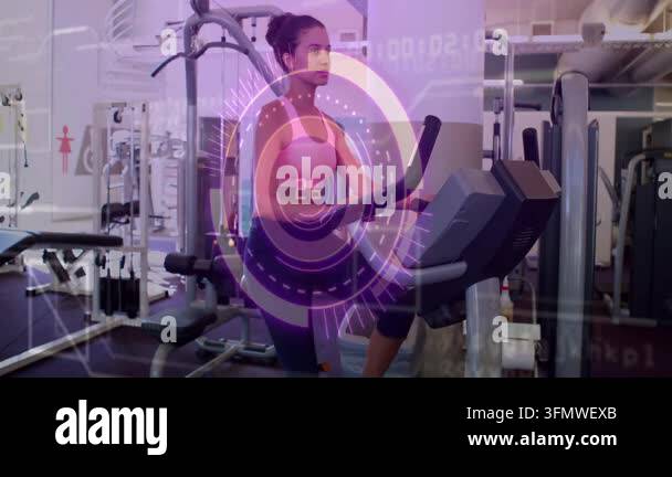 Woman stepping onto elliptical and holding grips in gym activating ...