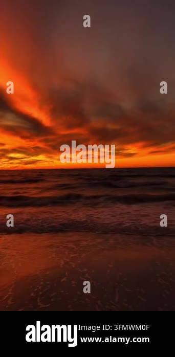 Dramatic sunset over the ocean with vibrant orange and red clouds ...