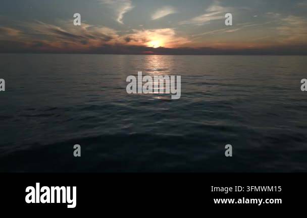 Serene ocean waves under a dramatic sunset sky with clouds, reflecting ...