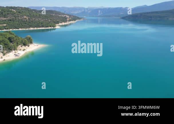 Aerial drone footage of a serene turquoise lake surrounded by lush ...