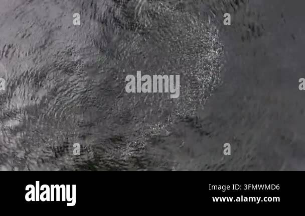 Abstract close-up of dark water surface with ripples and reflections ...