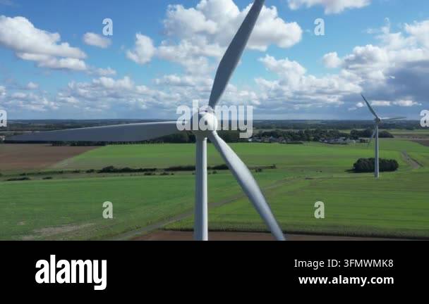 Aerial view of wind turbines spinning in a green field under a cloudy ...