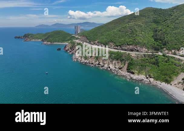 Aerial view of green mountains and winding road on blue sea rocky coast ...