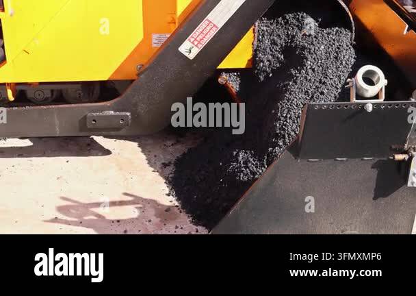 Construction paving machine is parked next to building site, tools are ...