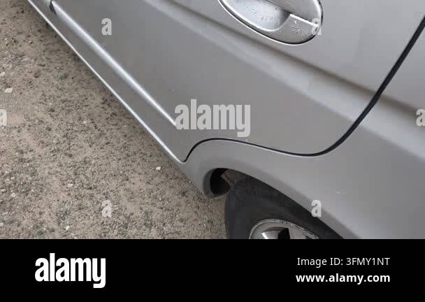 Close-up side view of a parked silver car on a rural dirt road. Focus ...