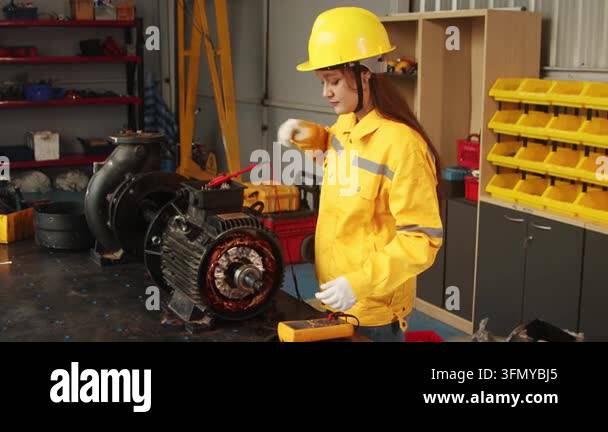 Beautiful engineer woman with helmet in safety clothing uses multimeter ...