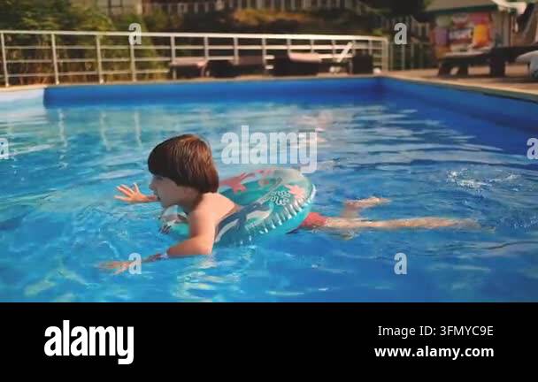 Cute Boy Swimming with Inflatable Ring in Pool and Looking at Camera ...