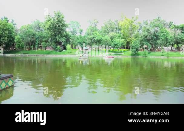 Panoramic view of a calm lake in a public park surrounded by lush green ...