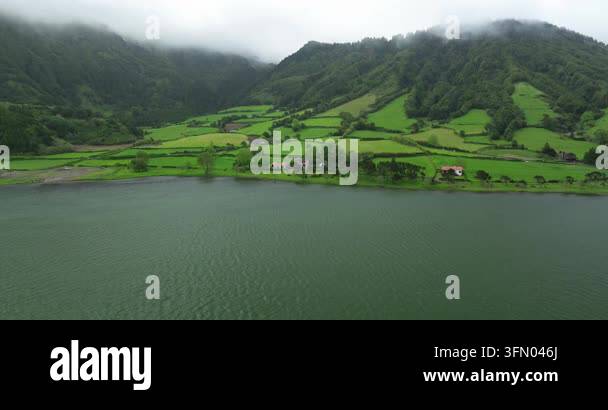 Aerial view of a green mountain slope and village by a lake Stock Video ...