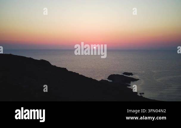 Beautiful sunset over the calm sea with dark rocky coastline Stock ...