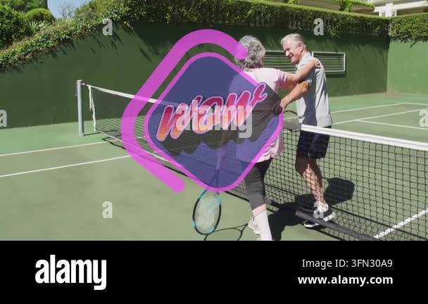 Senior couple hugging over tennis net, displaying fitness theme with ...