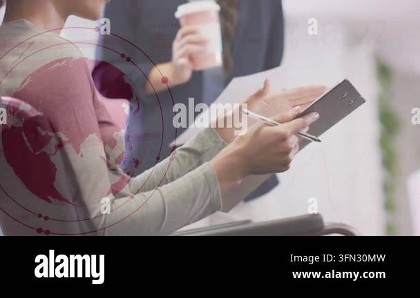 Two women reviewing tablet in business, standing woman offering paper ...