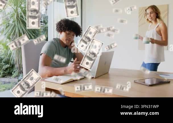 Man using laptop writing note as money bills falling obscuring faces ...