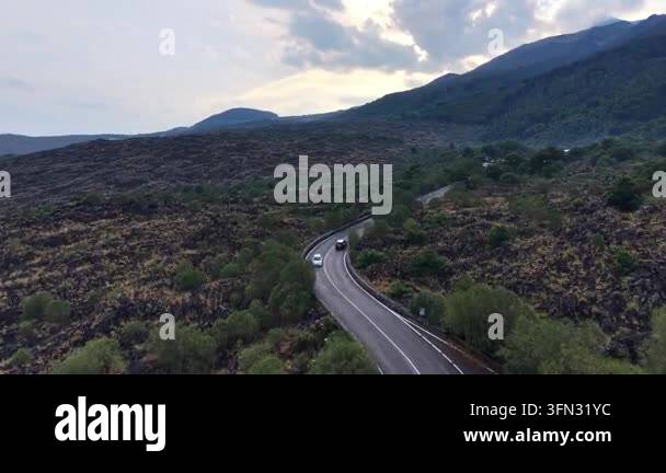 Volcantic Rocks Car navigate winding road through lush green landscape surrounded by ...