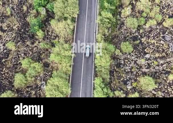 Aerial view of a car navigating a winding mountain road surrounded by ...
