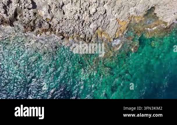 Aerial view of rocky coastline with turquoise waters and waves crashing ...