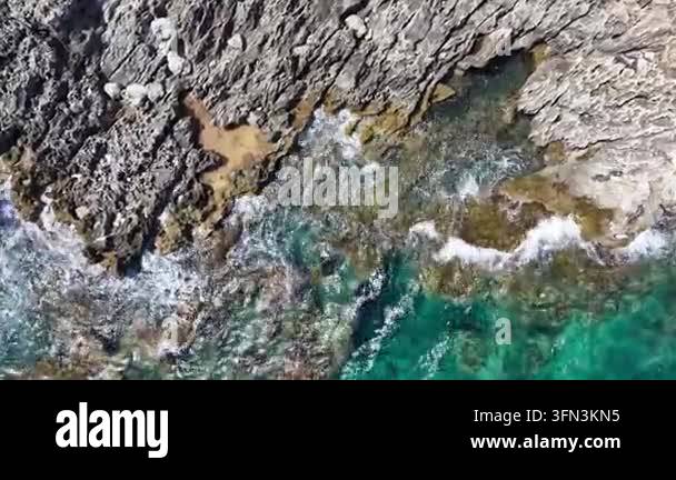 Aerial view of crashing sea waves against rocky coastline, showcasing ...