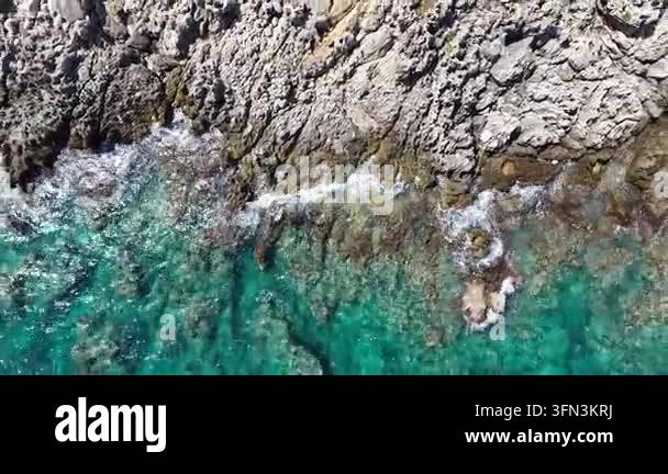 Aerial view of rocky coastline with turquoise waters and waves crashing ...