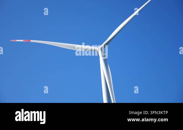 Wind turbine blades rotating gracefully against a clear blue sky ...