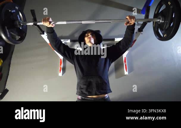 Strong sporty man doing bench press workout with a barbell at fitness ...