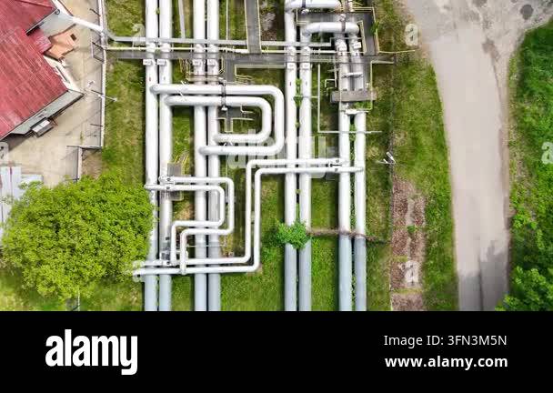 Aerial view of interconnected industrial pipes with green grass and ...