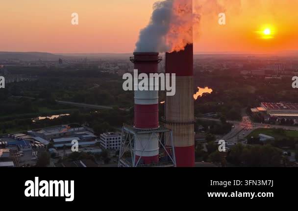 Industrial smokestack emits steam against a vibrant sunset backdrop ...