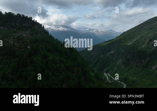 Aerial view of winding mountain road through lush green valley towards ...