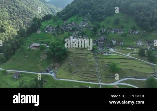 Aerial view of a small village nestled in a lush green mountain valley ...