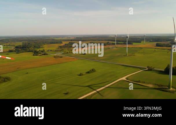 aerial view of wind turbines spinning in green fields on a sunny day ...
