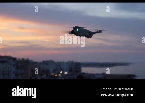 Drone flying over a coastal town at sunset with colorful clouds in the ...