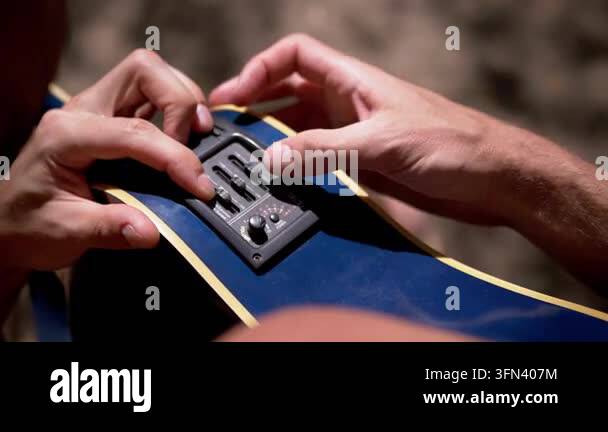 Musician adjusts the onboard equalizer sliders and volume knob on an ...