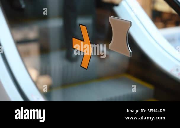 Close-up of an orange arrow sign pointing right on a glass surface ...