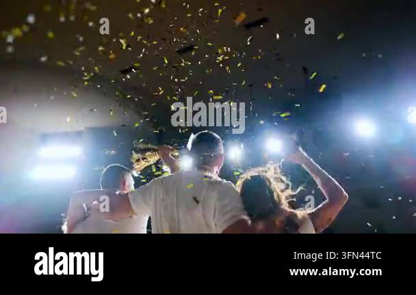 Successful team celebrates together with raised arms under falling ...