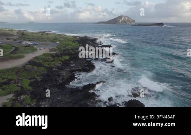 Volcantic Rocks Ocean waves crashing against dark volcanic coastline, distant island ...
