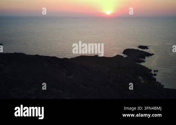 Sunset over calm ocean with rocky shoreline Stock Video Footage - Alamy