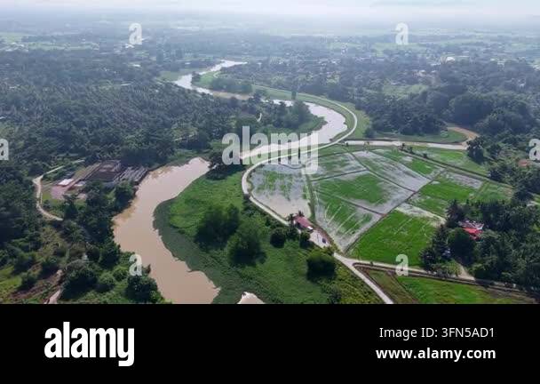 Aerial view of a winding river through green fields. Fields lie flooded ...