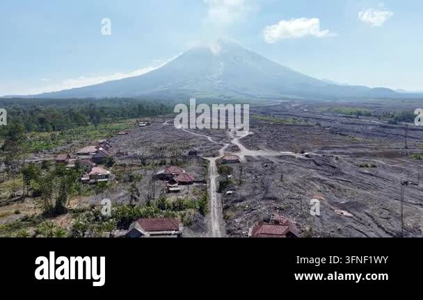 Volcano looms over scorched earth and scattered homes. Smoke drifts ...
