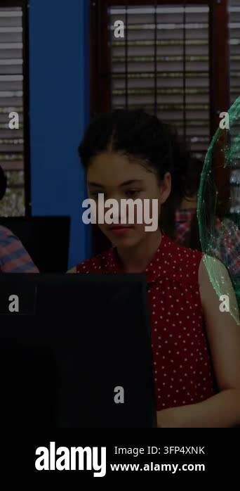 Teen girl reading and typing at monitor in school lab, green sphere ...