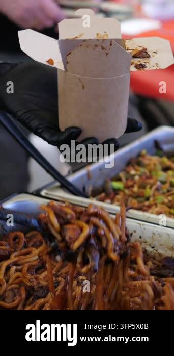 Lift Insect Vendor lifts cooked mealworms from serving tray and transfers them into ...
