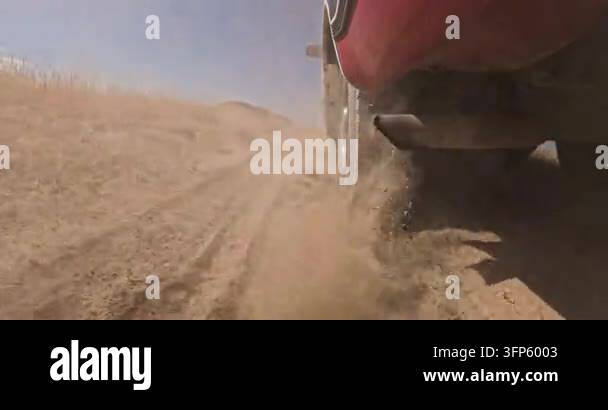 Cart Rutz Red vehicle kicks up dust on dry dirt road. Tire tread creates deep ...