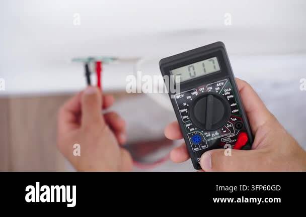 Socket Multimeter Hands testing an electrical outlet with a digital multimeter at home ...